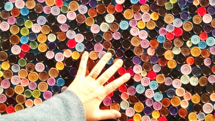 A hand reaching out to touch a large box of buttons.