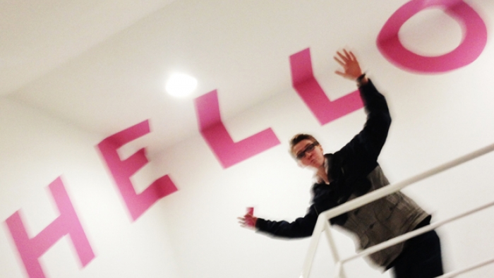A man stands at the top of a set of stairs inside a building, with 'Hello' written on the walls and ceiling of the building.