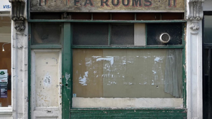 An old boarded-up shop with 'Tea Rooms' painted above it.