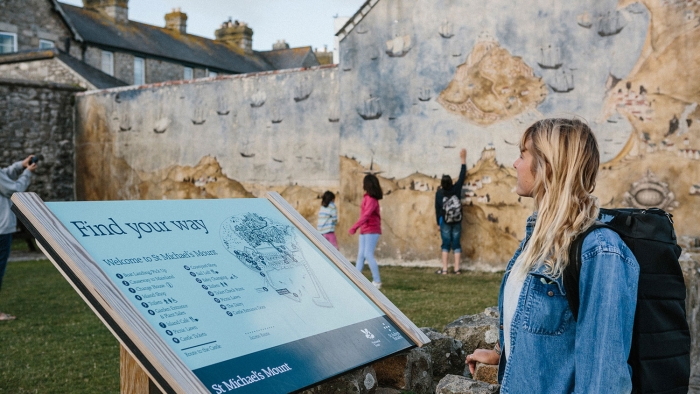 A woman looking at an information sign on St Michael's Mount.