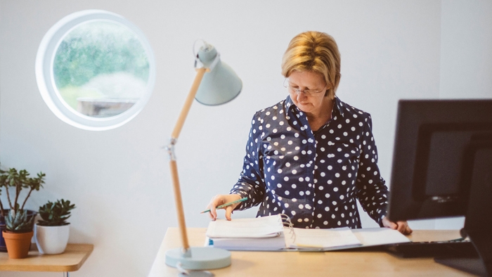 A woman looks through a folder at her desk in Latitude50's bright office space.
