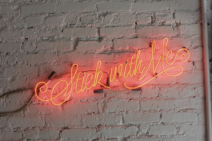 A neon sign reading 'Stick with me'.