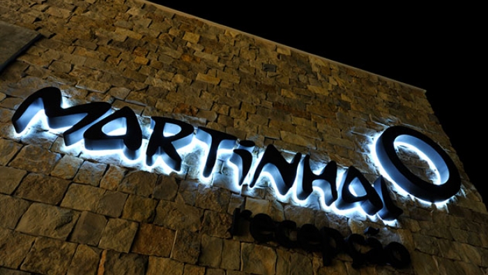 A building sign that reads: 'Martinhal', lit up at night.