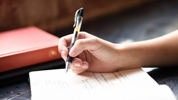 A hand holding a pen poised above a notepad.