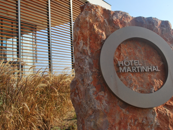 A metal sign reading 'Hotel Martinhal' on a rock.