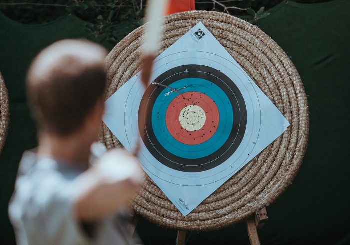 A man takes aim at an archery target with his bow and arrow.