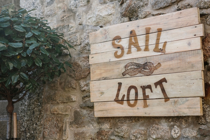 A wooden sign for the Sail Loft, with the logotype laser-etched onto wood.