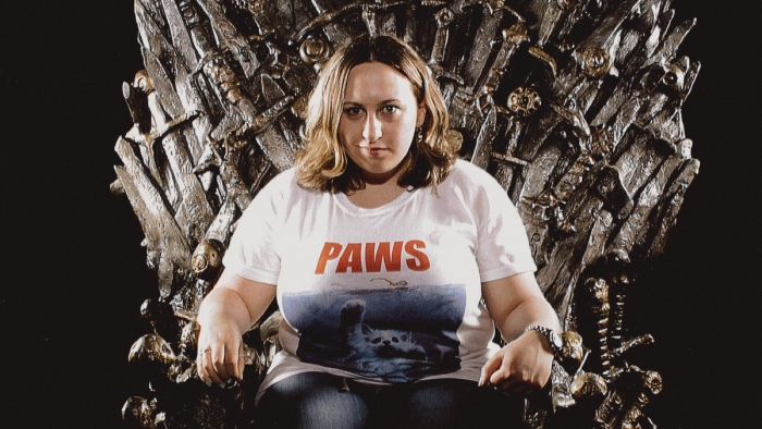 A woman sits the Iron Throne.