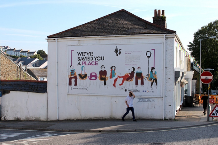 A billboard on the side of a building with an advert from Falmouth University.