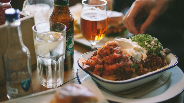 A big bowl of Mexican food being placed on a table.